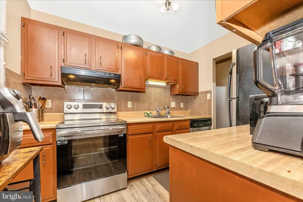 a kitchen with stainless steel appliances granite countertop a stove a sink and a refrigerator