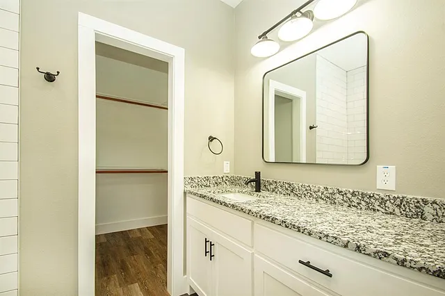a bathroom with a granite countertop sink and a mirror