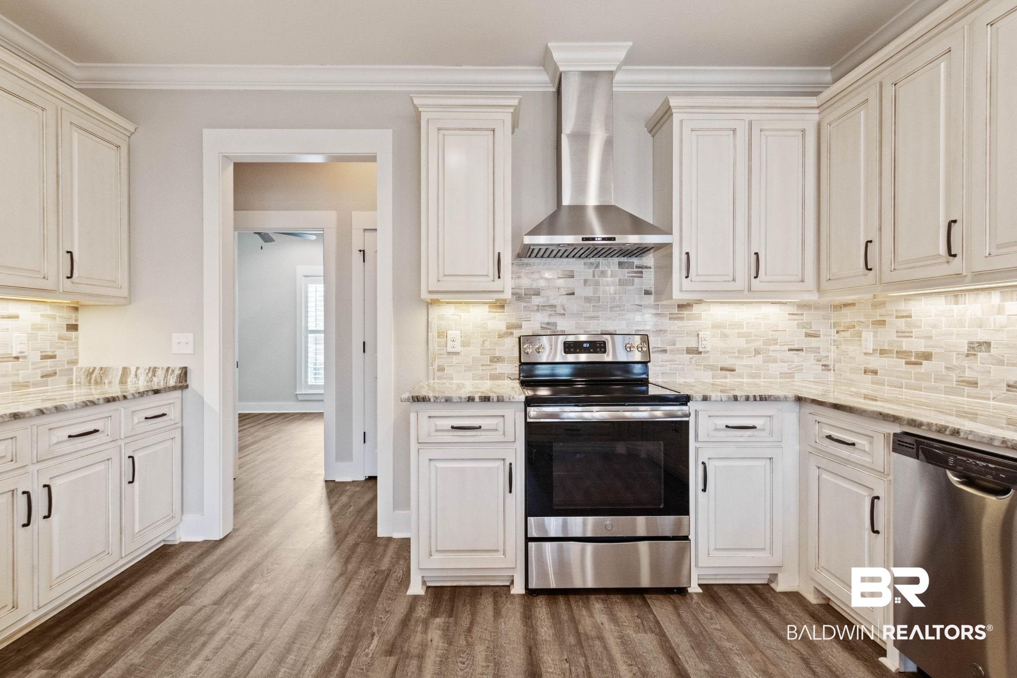 17376 Bankhead Boulevard Fairhope, AL 36532 - Photo 24 of 73 Kitchen featuring appliances with stainless steel finishes, light stone countertops, wall chimney range hood, and crown molding