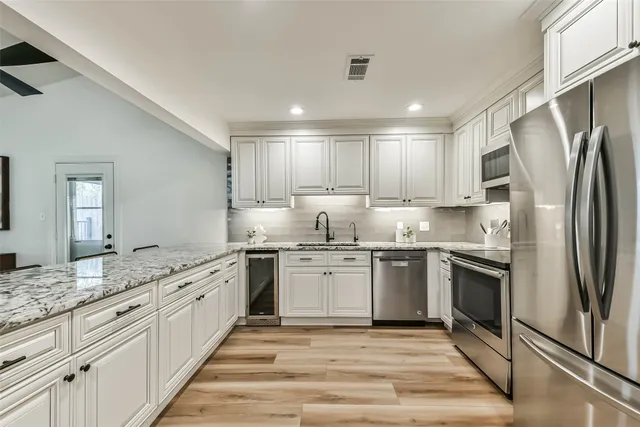 a kitchen with granite countertop stainless steel appliances a sink and cabinets