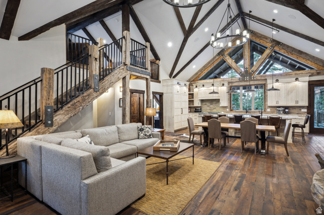 1667 West Tollgate Cyn Road Coalville, UT 84017 - Photo 21 of 61 Open-concept living space featuring vaulted ceilings with exposed wood beams, a prominent staircase with wood newel posts and metal balusters, and wood-finish flooring