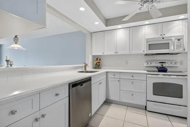 a kitchen with white cabinets and white appliances