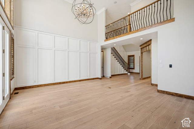 Living room, Formal Dining or Piano & Sitting room off the entry, study and family room with high ceilings,  an exposed beam, light wood-finish flooring, white wainscoting, and a wrought iron chandelier.
