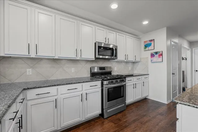a kitchen with stainless steel appliances granite countertop a stove a sink and a refrigerator
