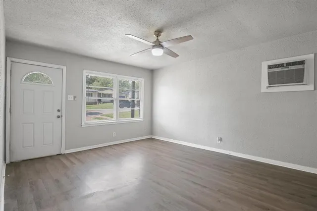 a view of an empty room with a window and wooden floor
