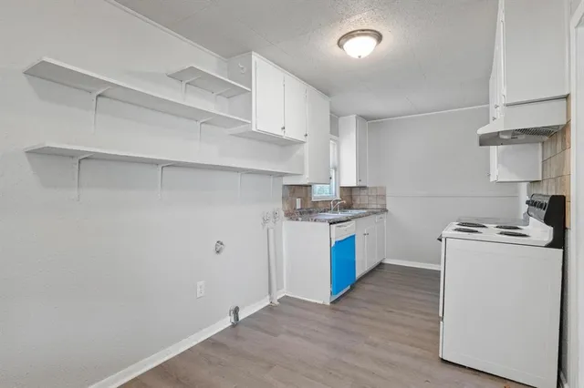 a kitchen with granite countertop a white stove top oven and white cabinets