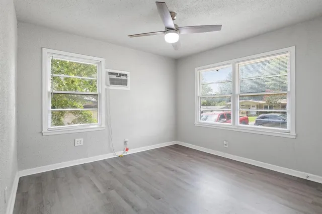 a view of an empty room with a window and wooden floor