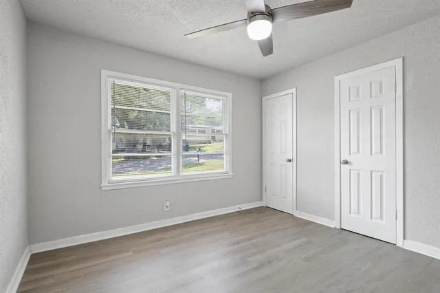 an empty room with a window and a ceiling fan
