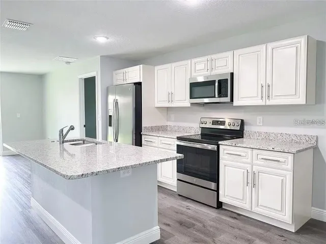 a kitchen with stainless steel appliances granite countertop a stove a sink and a microwave