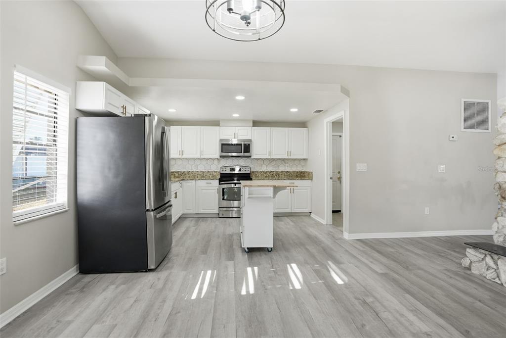 7026 Whitethorn Court Port Richey, FL 34668 - Photo 15 of 45 a kitchen with a refrigerator a sink and dishwasher a stove top oven with wooden floor