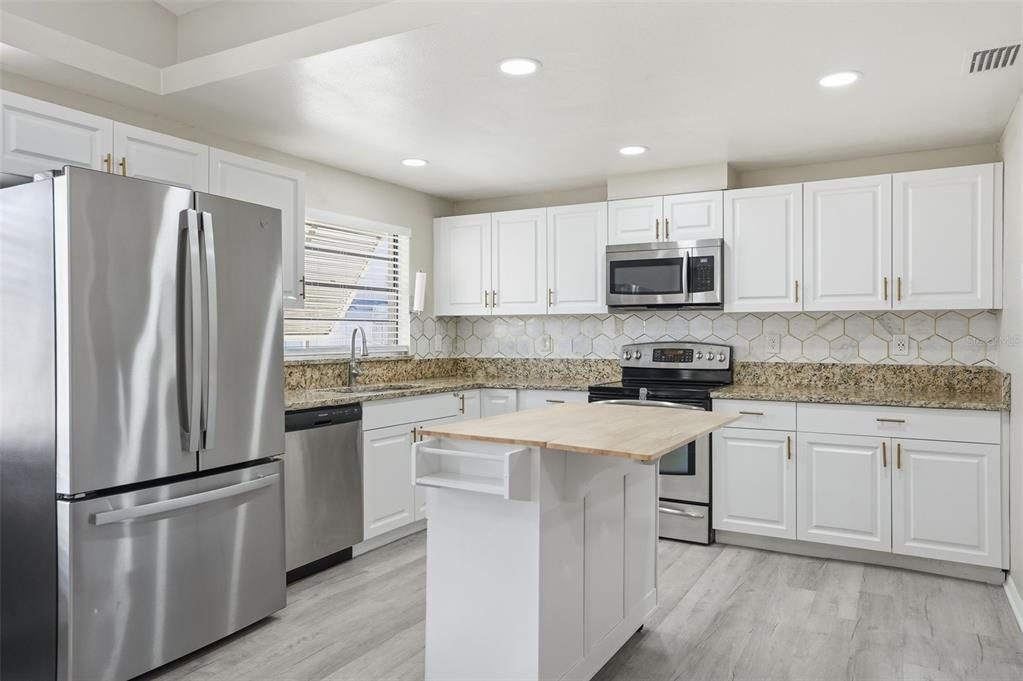 7026 Whitethorn Court Port Richey, FL 34668 - Photo 16 of 45 a kitchen with white cabinets and stainless steel appliances