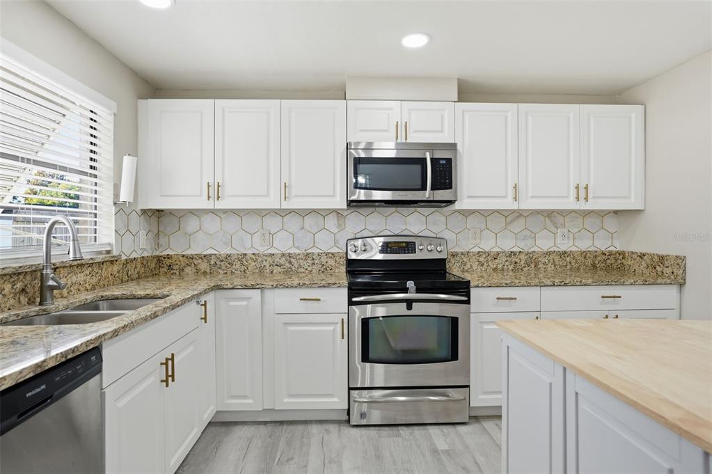 7026 Whitethorn Court Port Richey, FL 34668 - Photo 20 of 45 a kitchen with white cabinets and white appliances