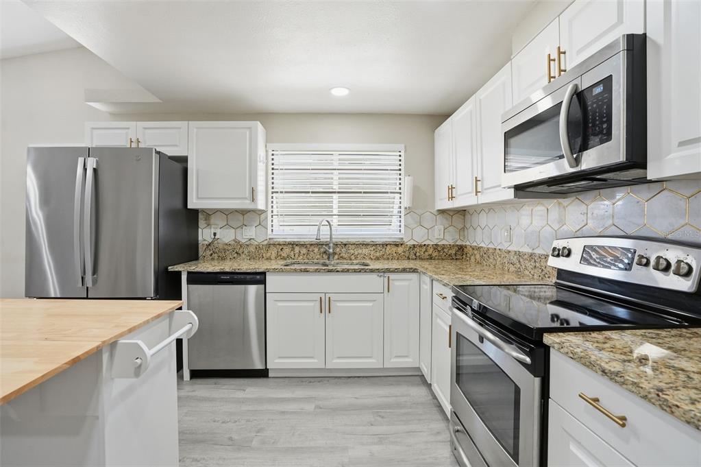 7026 Whitethorn Court Port Richey, FL 34668 - Photo 21 of 45 a kitchen with stainless steel appliances granite countertop a sink stove microwave and refrigerator