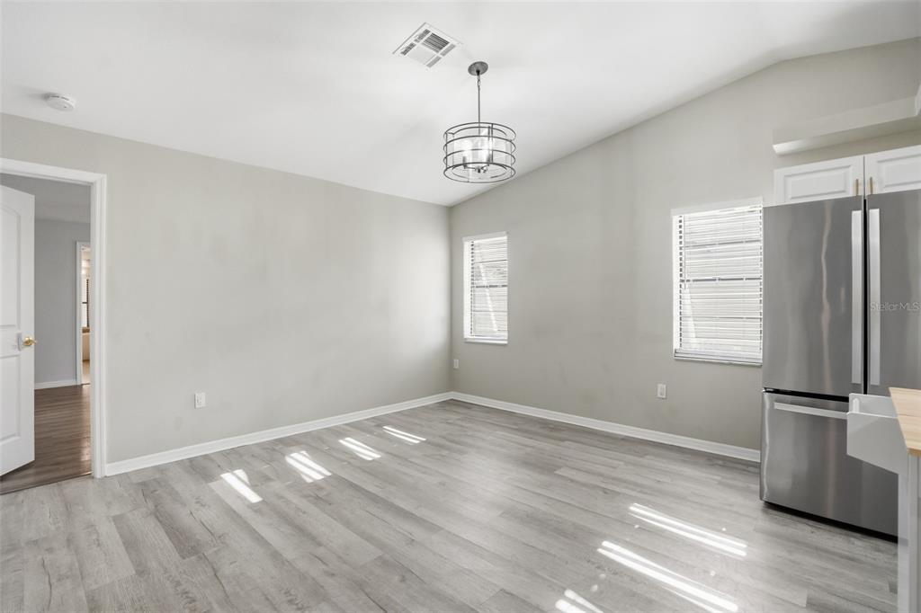 7026 Whitethorn Court Port Richey, FL 34668 - Photo 24 of 45 an empty room with wooden floor kitchen view and windows