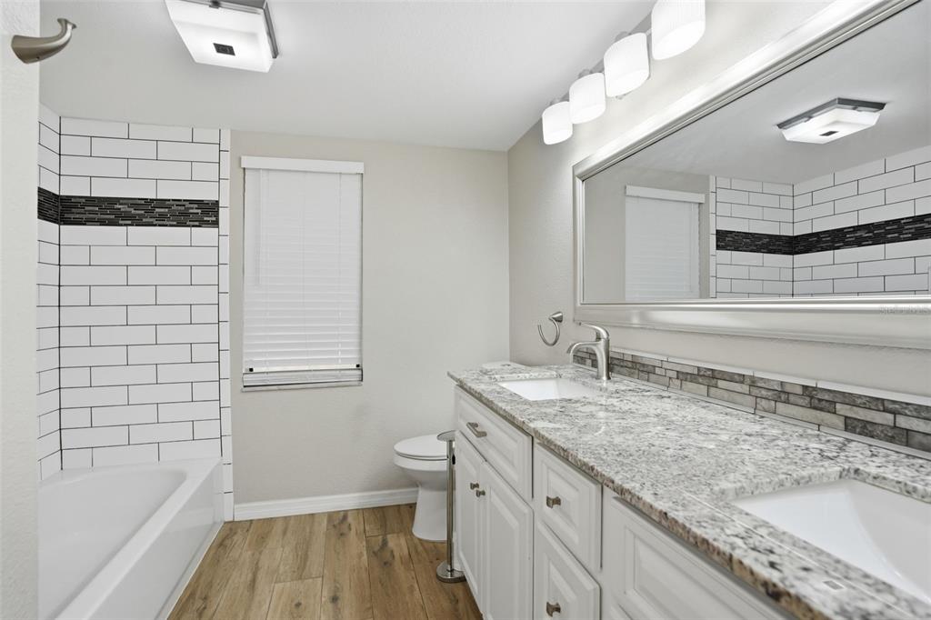 7026 Whitethorn Court Port Richey, FL 34668 - Photo 34 of 45 a bathroom with a granite countertop sink a toilet and bathtub