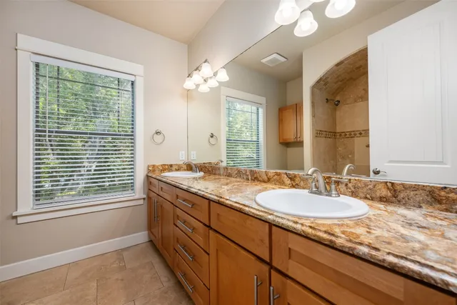 a bathroom with a granite countertop sink a large mirror a and a window
