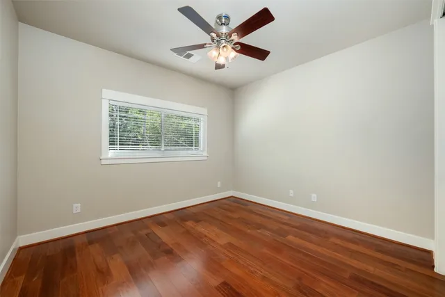 a view of an empty room with window and wooden floor