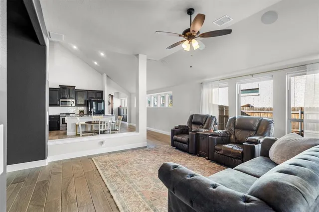 a living room with furniture kitchen view and a wooden floor