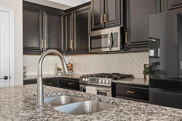 a kitchen with stainless steel appliances granite countertop a sink stove and refrigerator