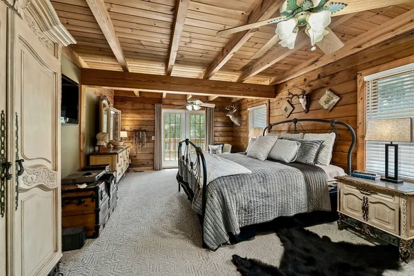 a spacious bedroom with a bed a flat screen tv and a chandelier