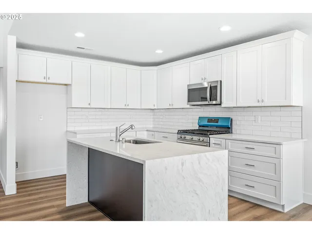 a kitchen with kitchen island a sink stainless steel appliances and cabinets