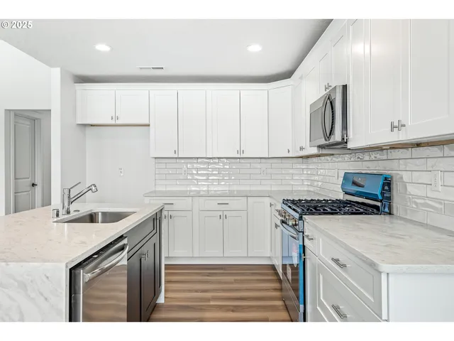 a kitchen with granite countertop a sink a stove and cabinets