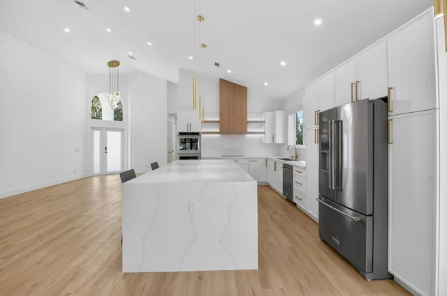 a large kitchen with stainless steel appliances kitchen island a large counter top and a refrigerator
