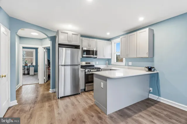 a kitchen with stainless steel appliances granite countertop a refrigerator a sink dishwasher a stove with wooden cabinets and floors