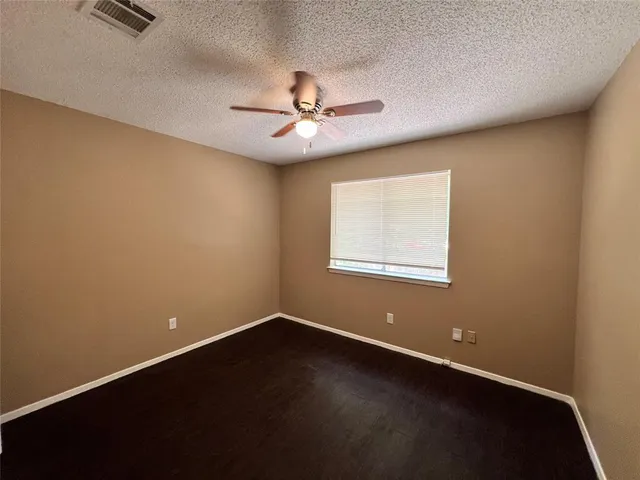 an empty room with a window and ceiling fan