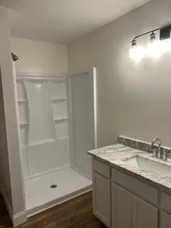 a bathroom with a granite countertop sink a mirror and shower