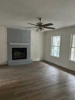 a view of an empty room with wooden floor fireplace and a window