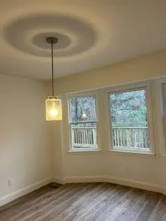 a view of an empty room with a window and wooden floor