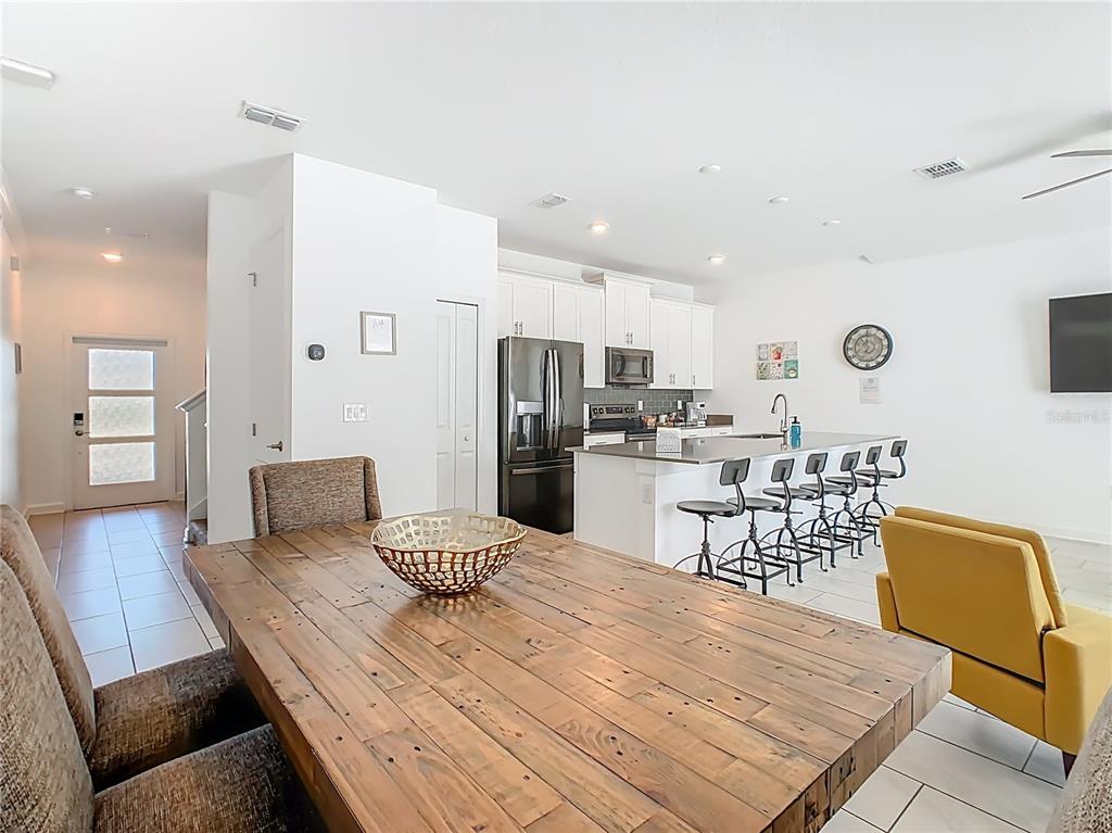 2957 Simile Street Kissimmee, FL 34746 - Photo 16 of 67 a kitchen with stainless steel appliances granite countertop a refrigerator a stove top oven and a dining table with wooden floor