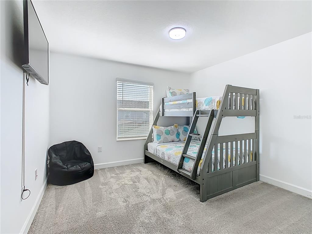 2957 Simile Street Kissimmee, FL 34746 - Photo 18 of 67 a bedroom with a bed and a flat tv screen on the dresser