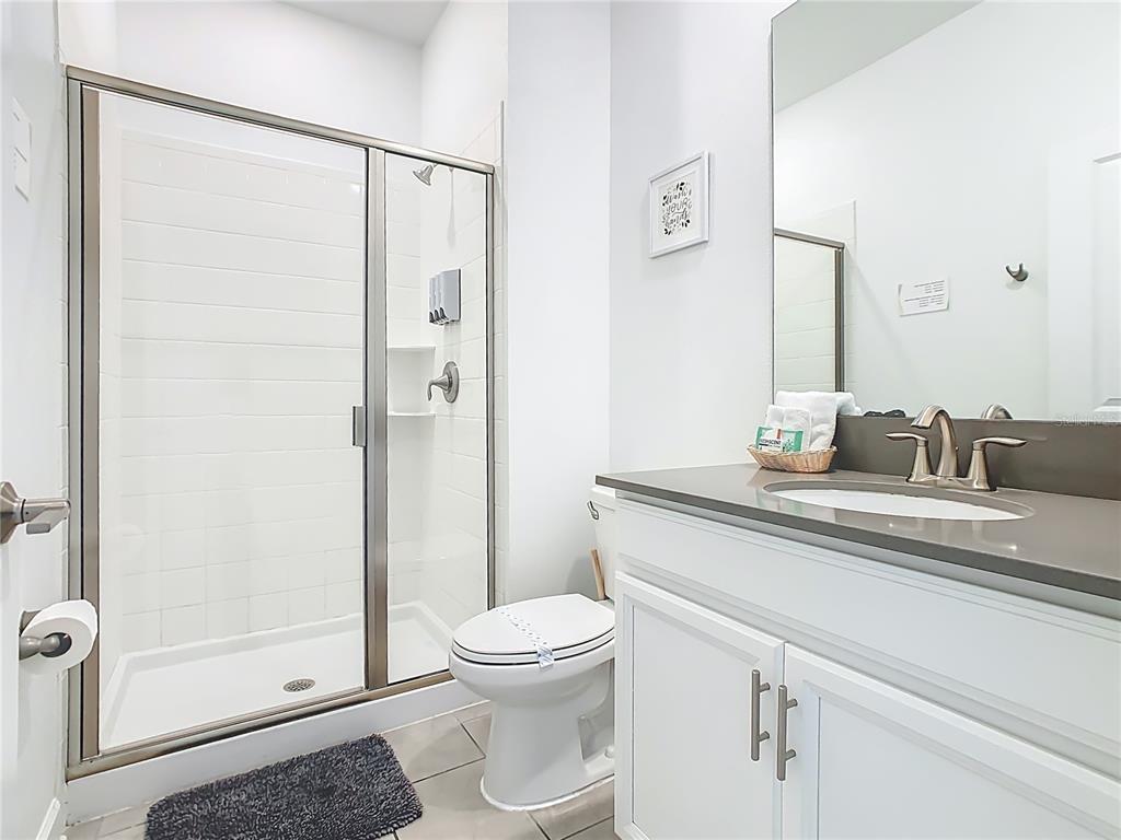 2957 Simile Street Kissimmee, FL 34746 - Photo 43 of 67 a bathroom with a granite countertop sink toilet and shower