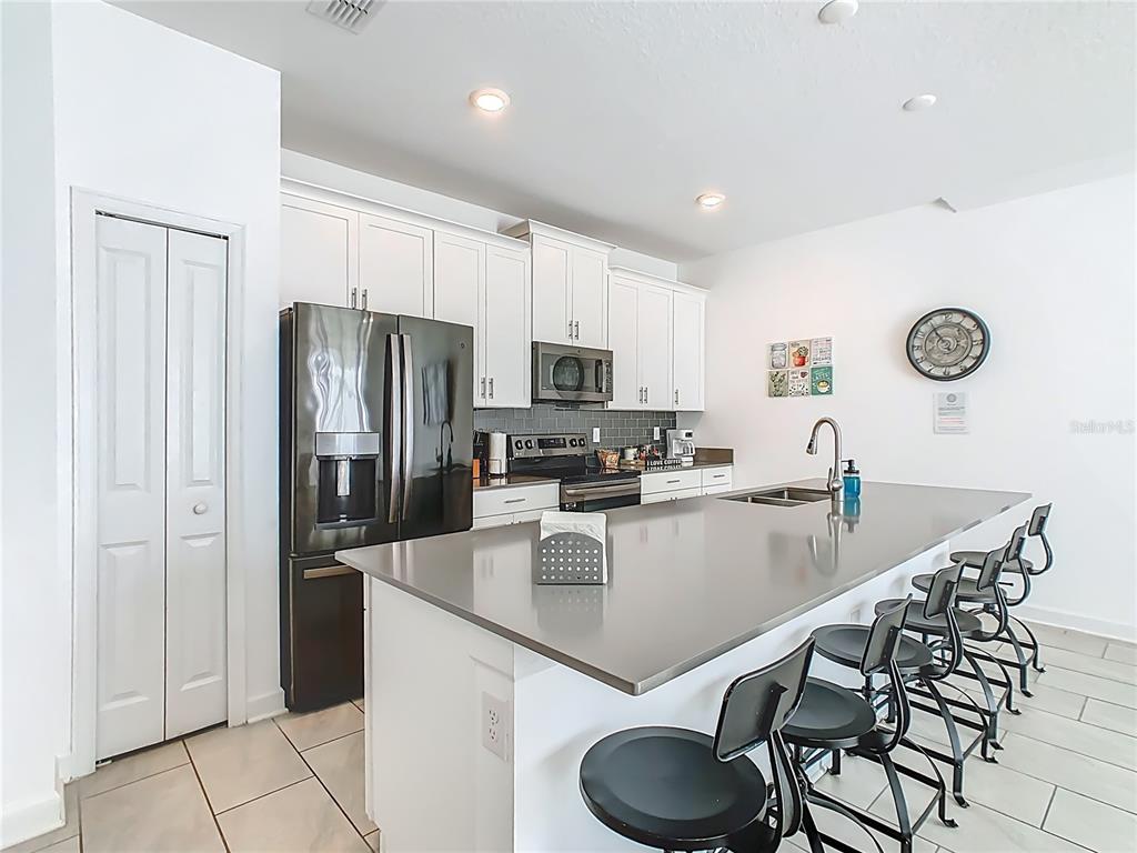 2957 Simile Street Kissimmee, FL 34746 - Photo 6 of 67 a kitchen with granite countertop a table chairs microwave and refrigerator