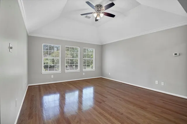an empty room with windows and chandelier fan
