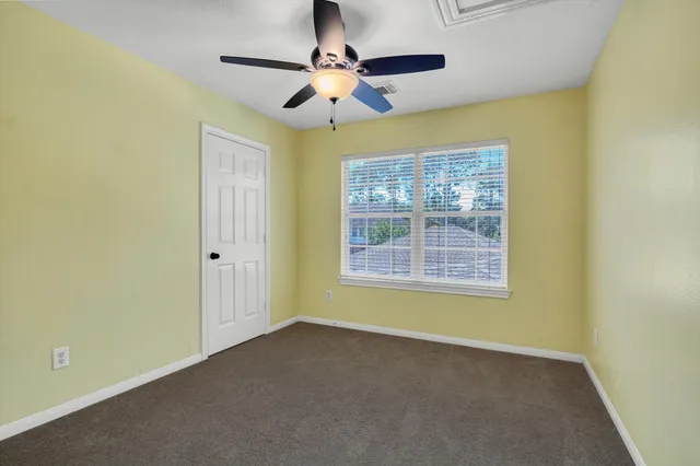 a view of an empty room with chandelier fan and a bathroom