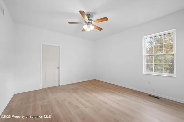 an empty room with a window and a fan