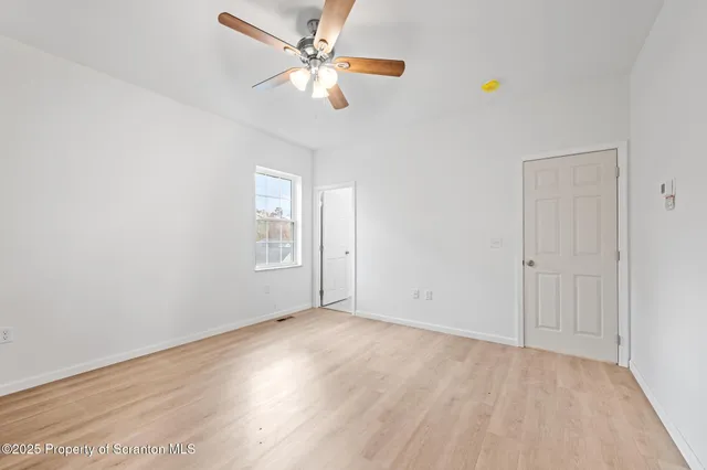 an empty room with closet and a ceiling fan