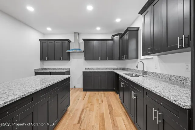 a large kitchen with a sink and a stove top oven with wooden floor