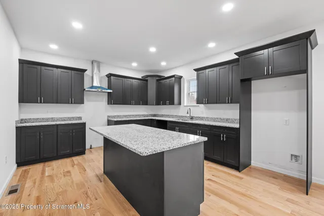 a kitchen with kitchen island granite countertop wooden cabinets and refrigerator