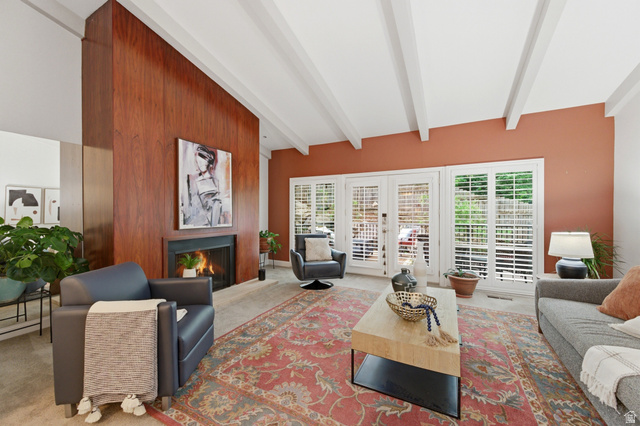 3674 Oak Rim Way Salt Lake City, UT 84109 - Photo 6 of 47 Living area featuring a floor-to-ceiling wood-paneled fireplace surround, vaulted ceilings with exposed beams, and multiple windows with plantation shutters