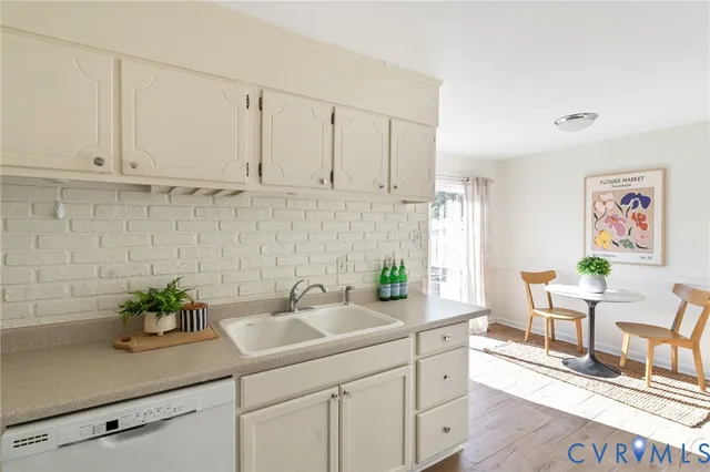 a kitchen with stainless steel appliances white cabinets a potted plant and a sink