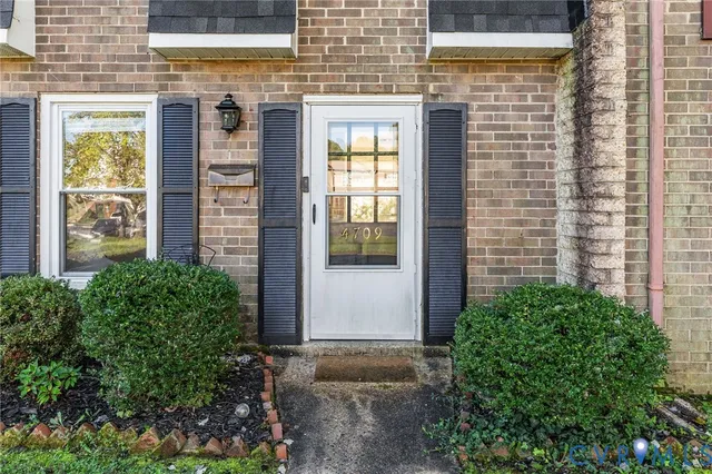 a view of a brick house with a large windows and plants