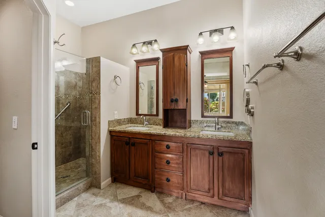 a bathroom with a granite countertop sink a mirror and a shower
