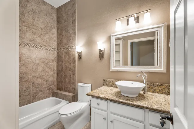a bathroom with a granite countertop toilet a sink and a mirror
