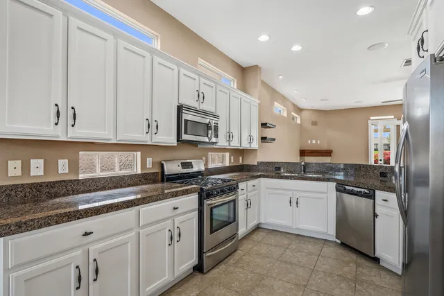 a kitchen with granite countertop white cabinets and stainless steel appliances