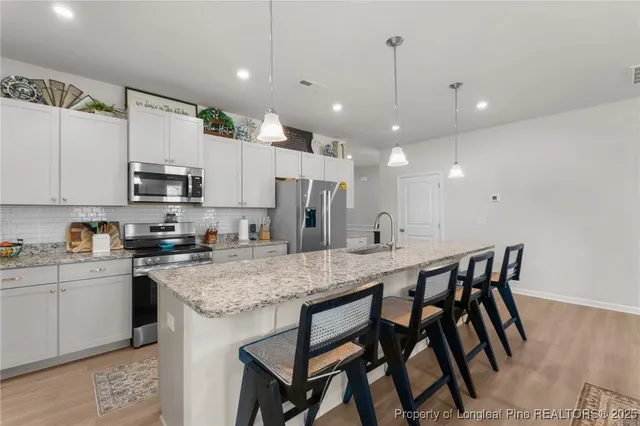 a kitchen with stainless steel appliances granite countertop a kitchen island hardwood floor and a sink