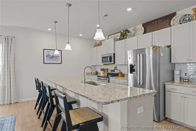 a kitchen with granite countertop kitchen island stainless steel appliances a refrigerator a stove a sink a center island a table and chairs
